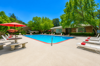 Community swimming pool with red umbrellas and lounge chairs